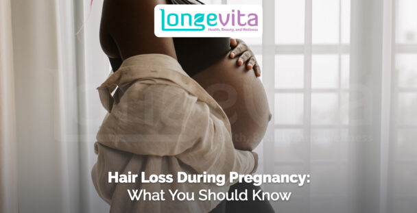 pregnant woman holding her bare belly in front of a window with light curtains