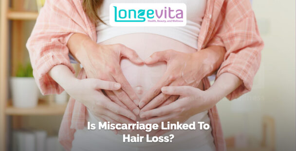 pregnant woman holding her belly with partner’s hands forming a heart shape