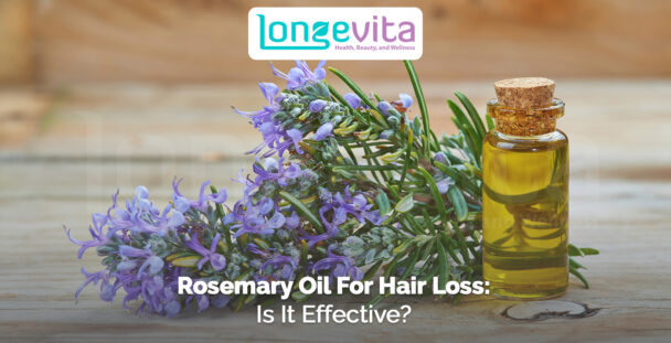 rosemary flowers and bottle of rosemary oil on wooden surface
