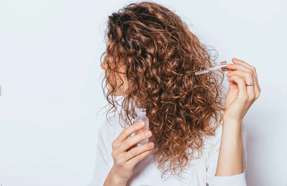 woman applying hair serum