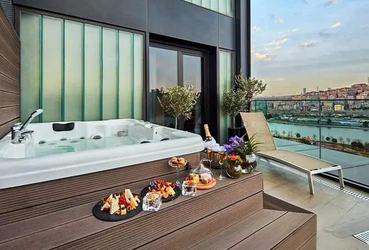 private terrace jacuzzi suite with city and river view, snacks, and drinks on wooden steps