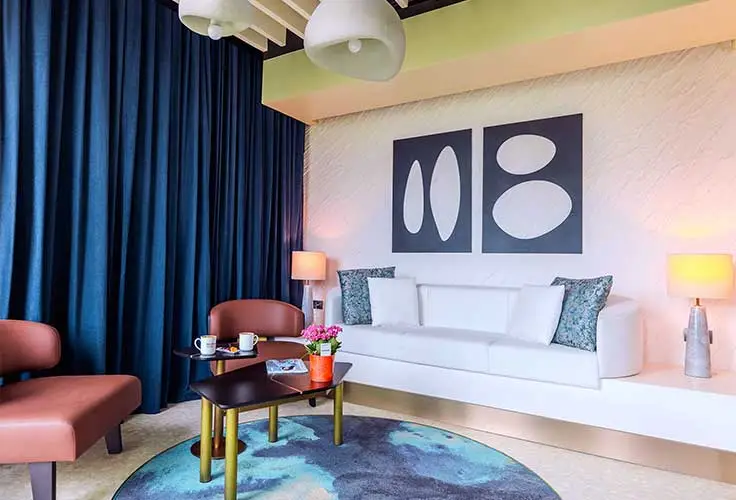 colorful and modern hotel suite lounge area with white sofa, abstract art, and coffee table