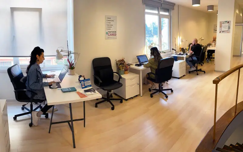 Four people working at their desks in an office area, focused on their computers.