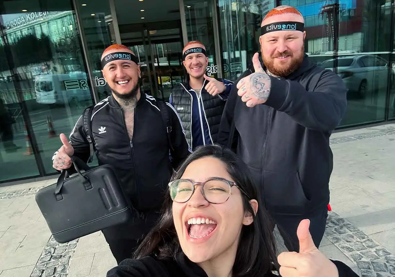 group of smiling hair transplant patients with headbands giving thumbs up outside clinic
