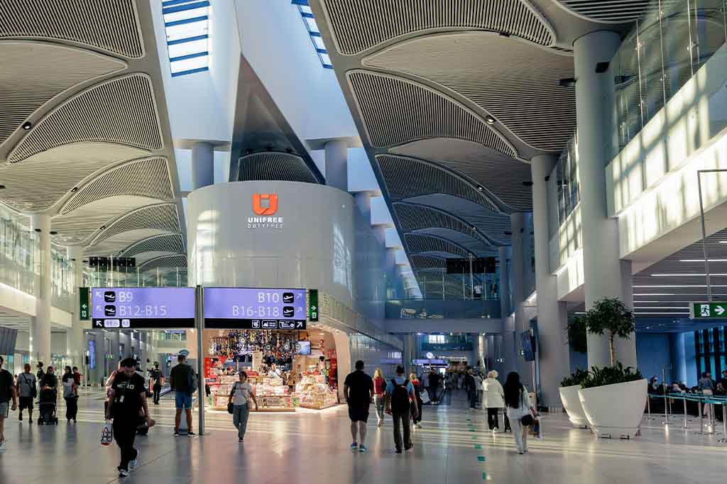 interior view of Istanbul Airport arrivals terminal with travelers and shops