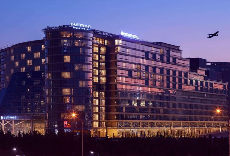 exterior of Pullman Istanbul Airport Hotel at night with illuminated windows and airplane in sky