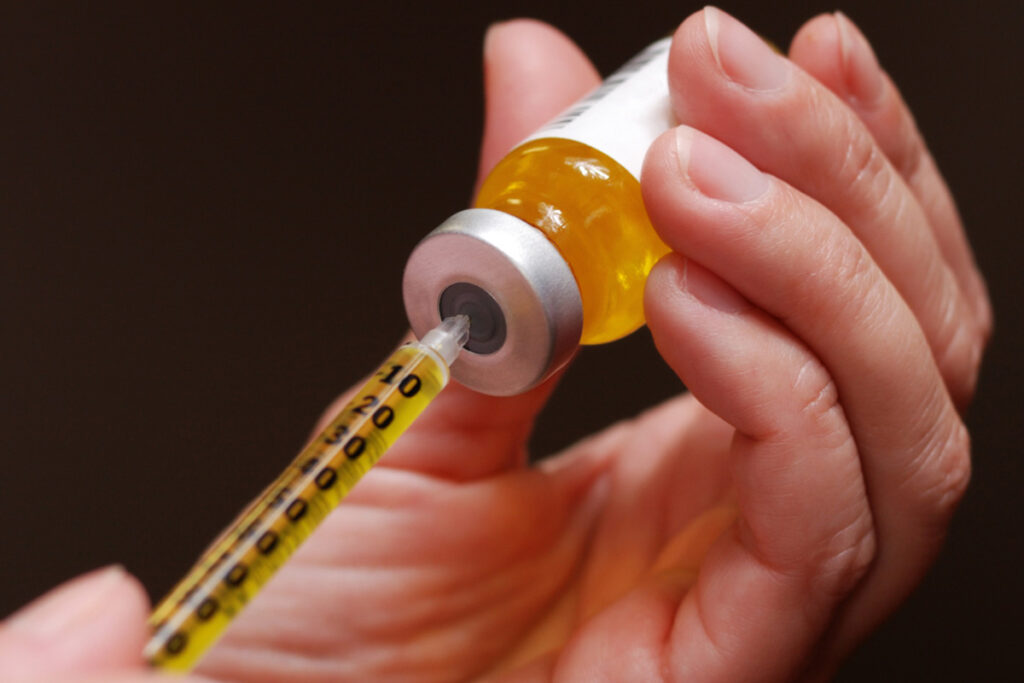 close-up of syringe drawing steroids from vial, representing medication caution.